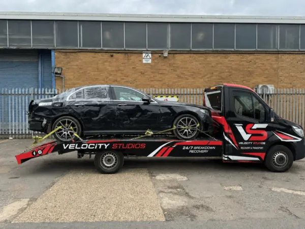 Velocity Studios recovery truck transporting a damaged black BMW